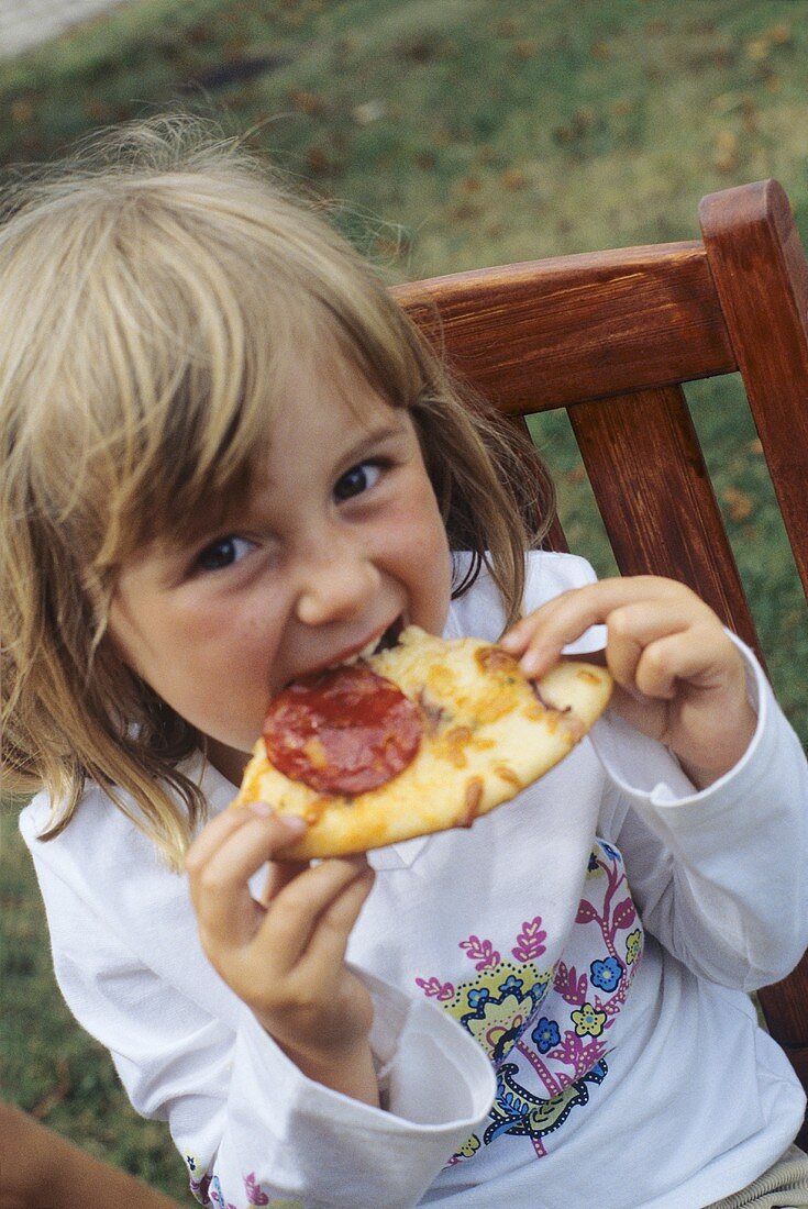 Mädchen isst Pizza im Freien