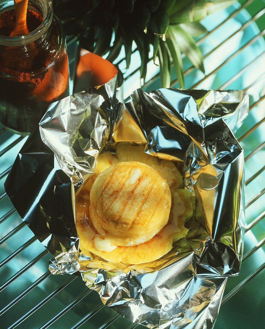 Goat's cheese barbecued in foil with honey and pineapple