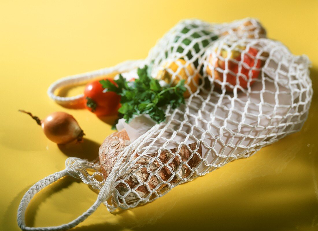 Net shopping bag full of vegetables and bread