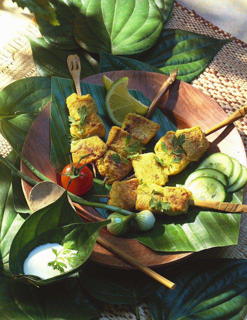 Geflügelspiesse auf Bananenblatt und Dip in Blatt-Schale