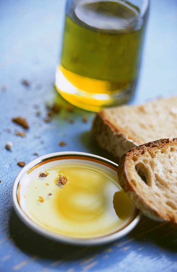 Olivenöl auf Teller mit Brotscheiben & Olivenölflasche
