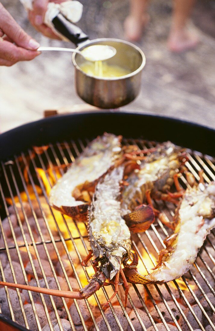 Langoustines on grill being drizzled with marinade
