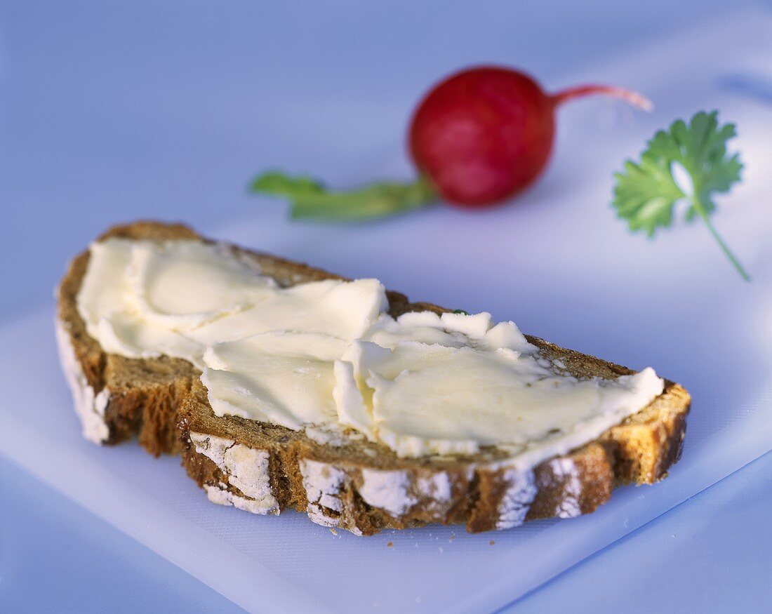 Eine Scheibe Butterbrot, dahinter Radieschen