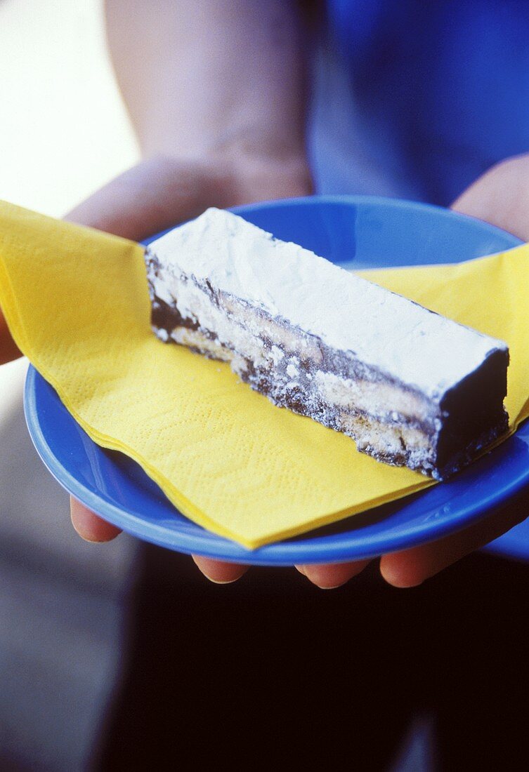 Hands holding plate with a chocolate biscuit bar