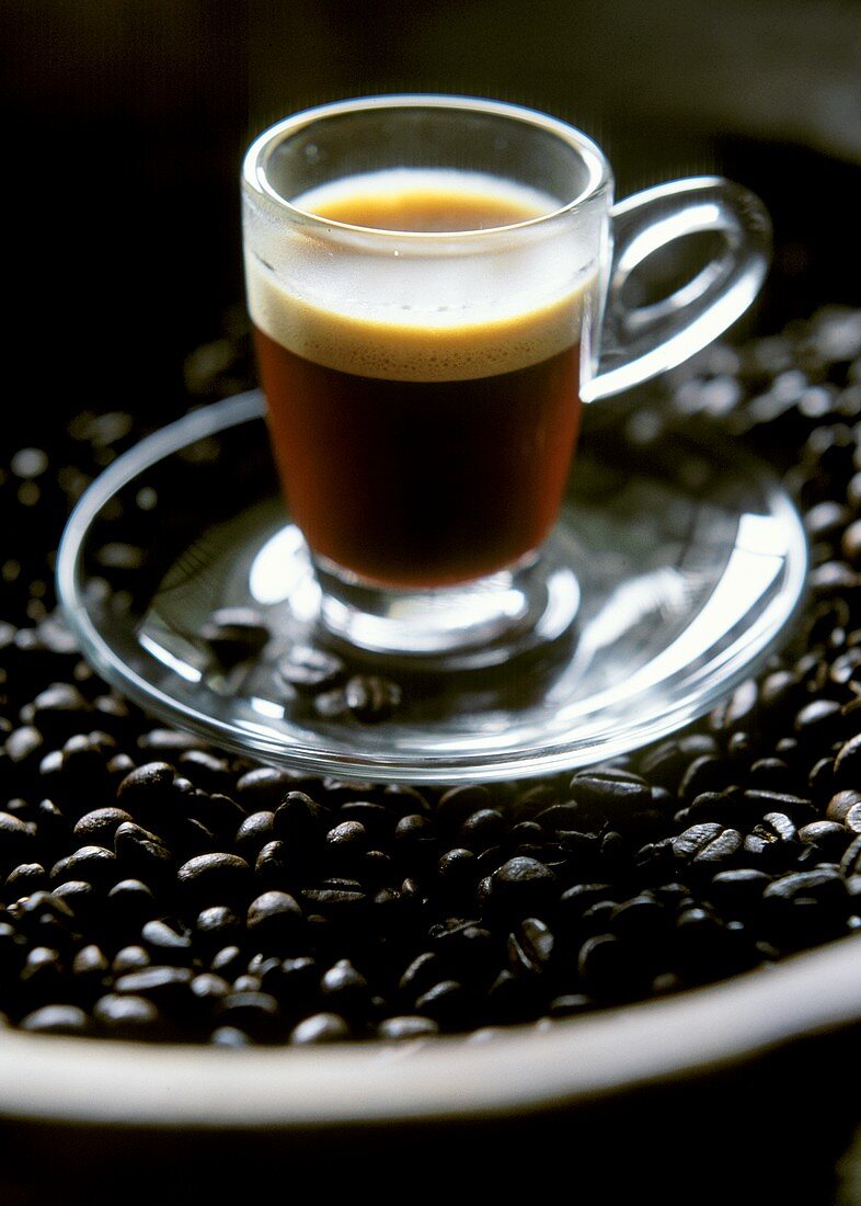 Espresso ("lengthened") in glass cup on coffee beans