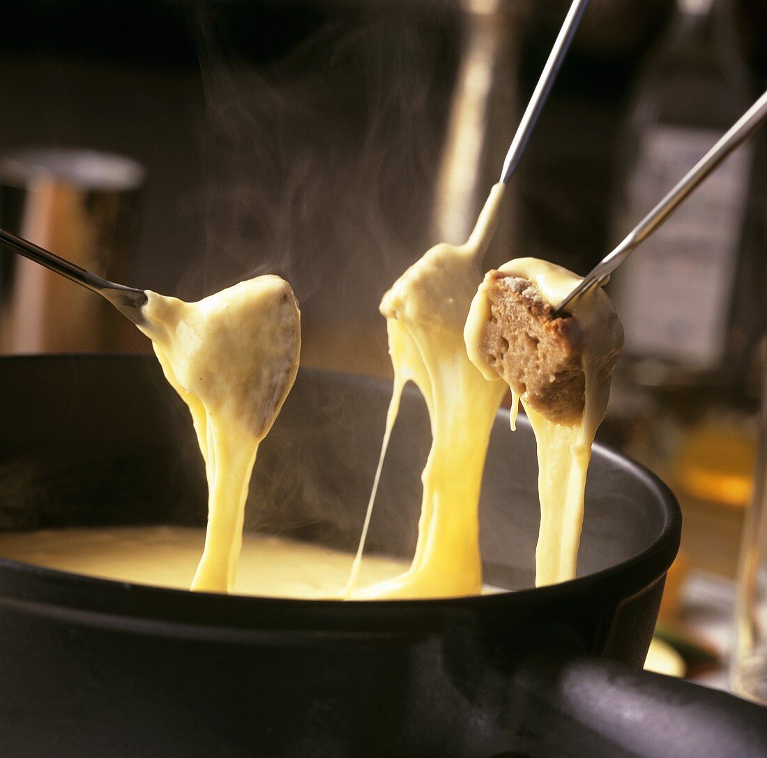 Käsefondue mit Brotwürfeln auf Fonduegabeln