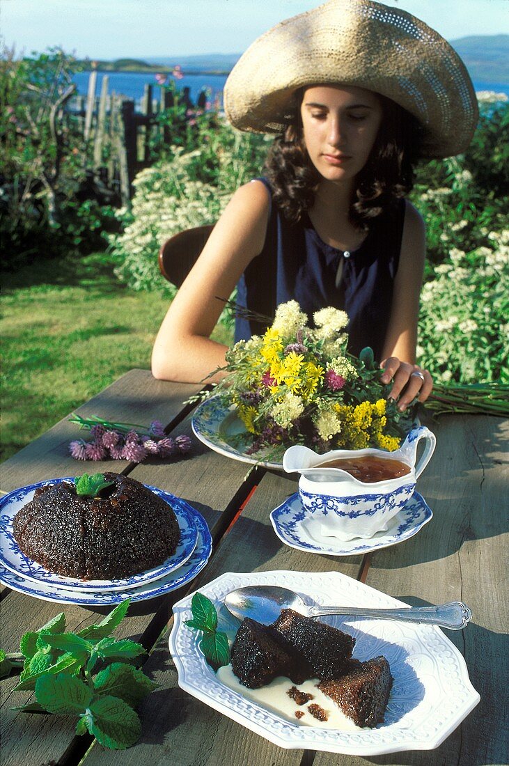 Scottish pudding on garden table, young woman behind