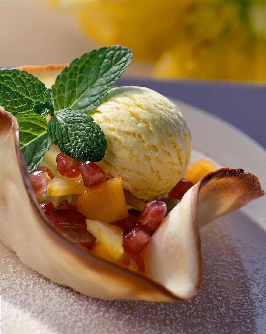 Fruit salad with scoop of ice cream in marzipan wafer bowl