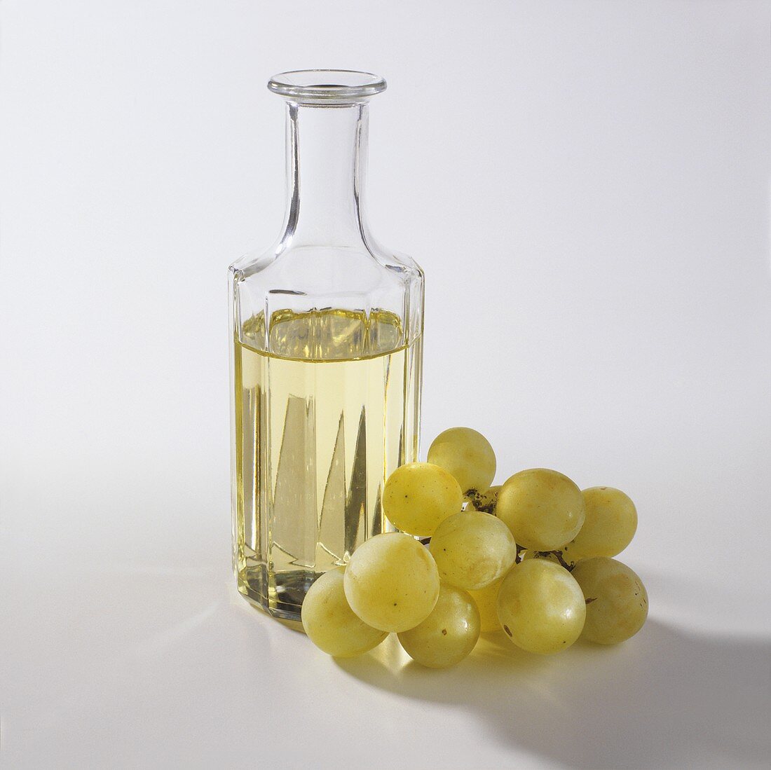 Traubenkernöl in einer Glasflasche, daneben Trauben