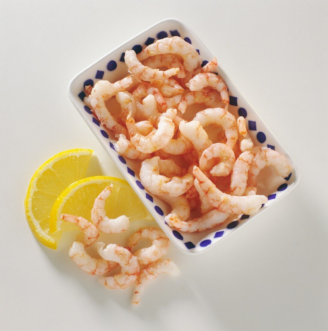 Shrimps in bowl and beside it with lemon wedges