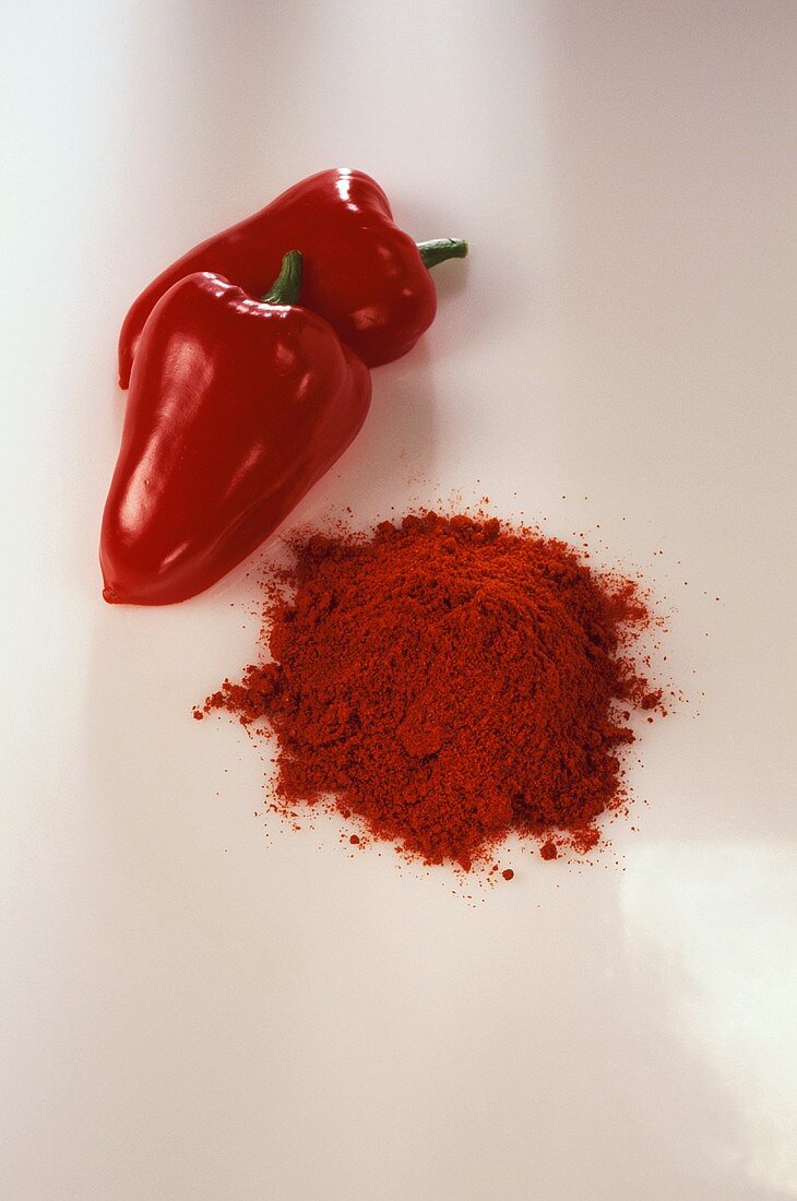Ein Häufchen Paprikapulver, daneben rote Paprika