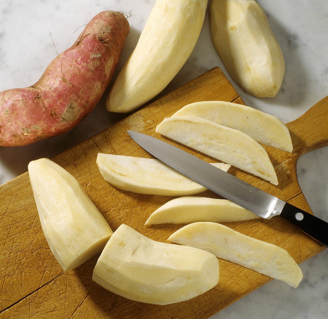 Cutting peeled sweet potatoes into wedges lengthwise