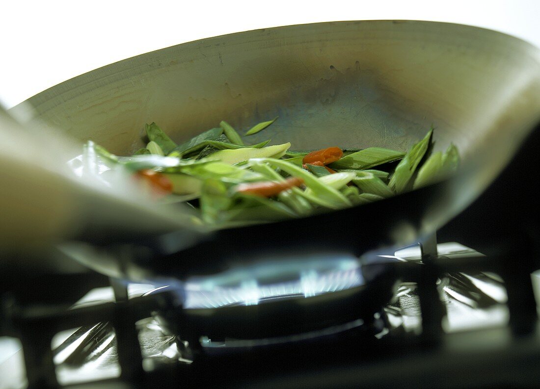 Gemüse im Wok auf einer Gasflamme