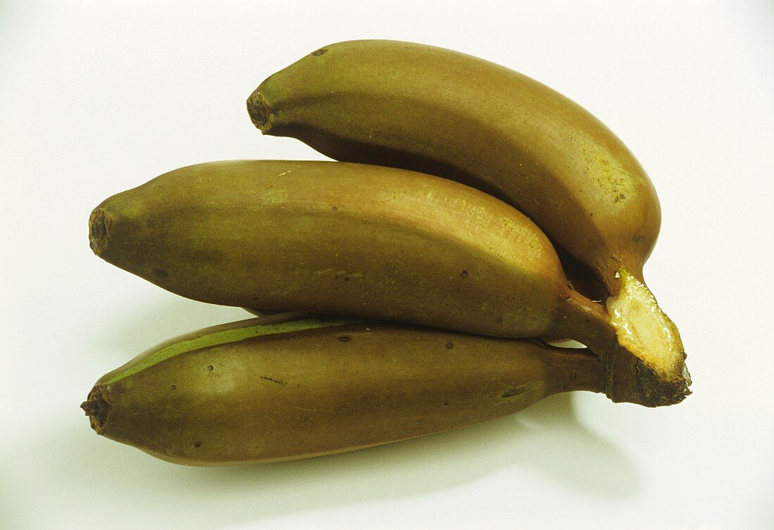 Three red bananas on banana leaf