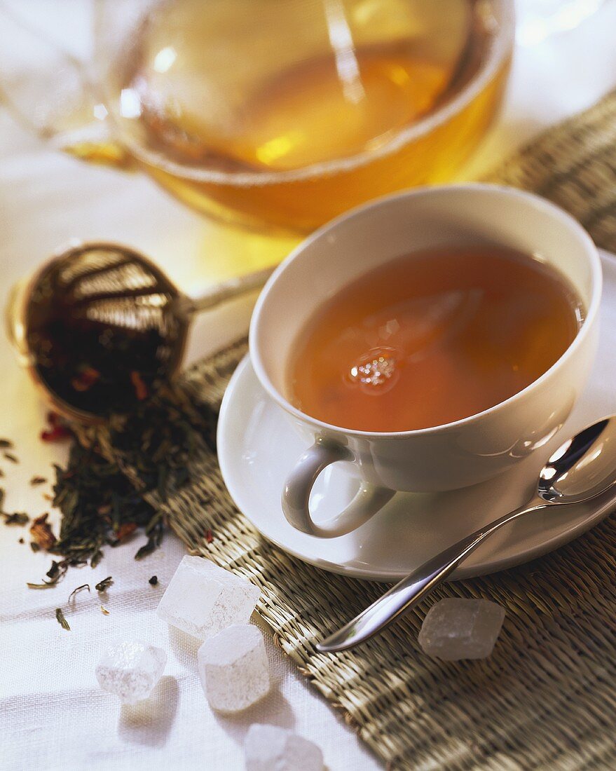 A cup of tea in front of glass teapot