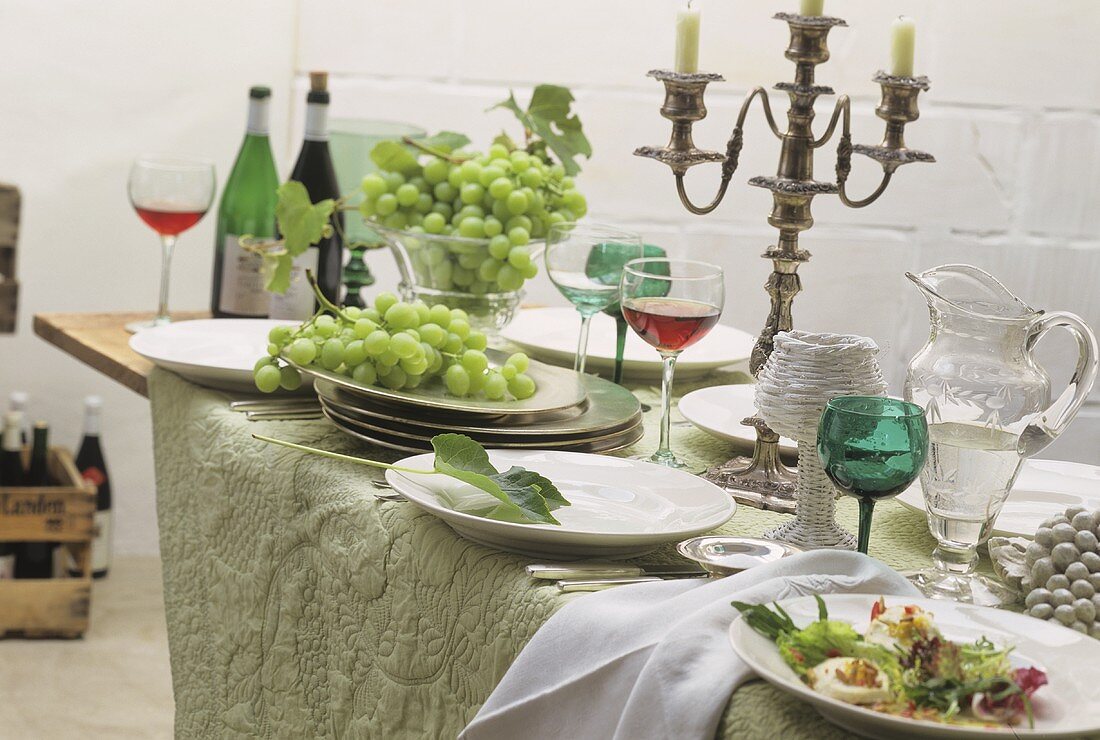 Improvisiertes Buffet auf Klapptisch mit Wein, Trauben, Salat