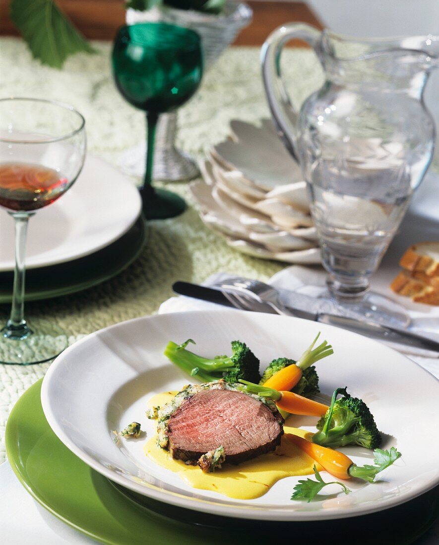 Beef fillet in herb crust on saffron sauce with vegetables