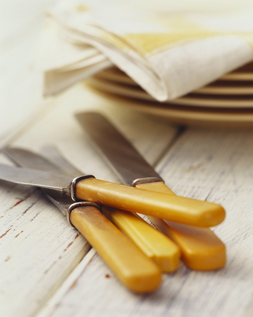 Knives, pile of plates with napkins behind