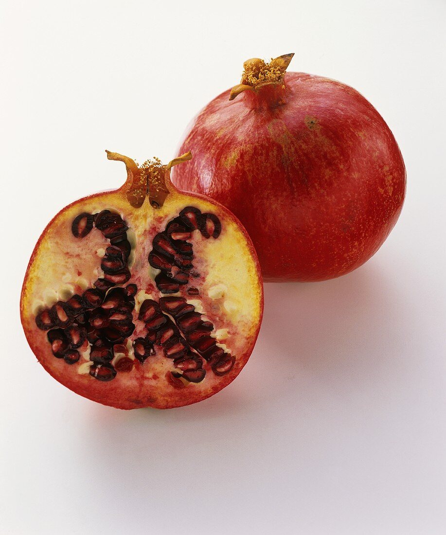 Pomegranate half in front of whole pomegranate