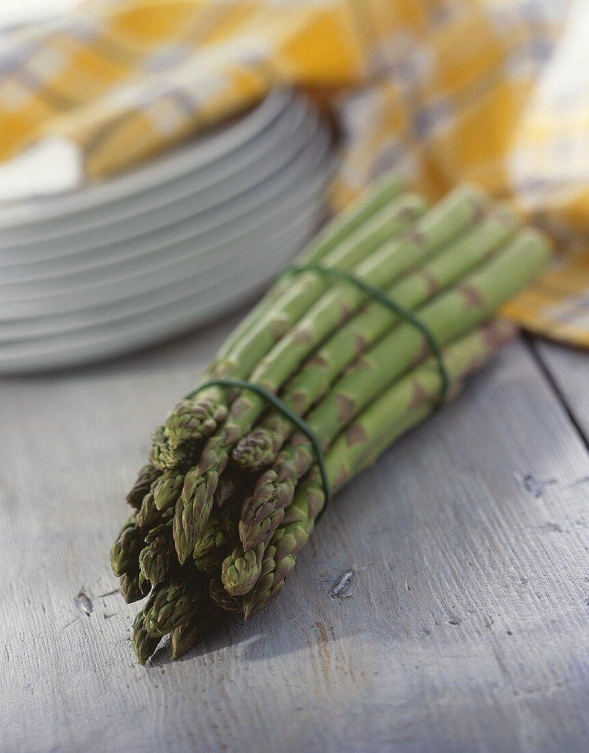 A bunch of green asparagus, plate behind