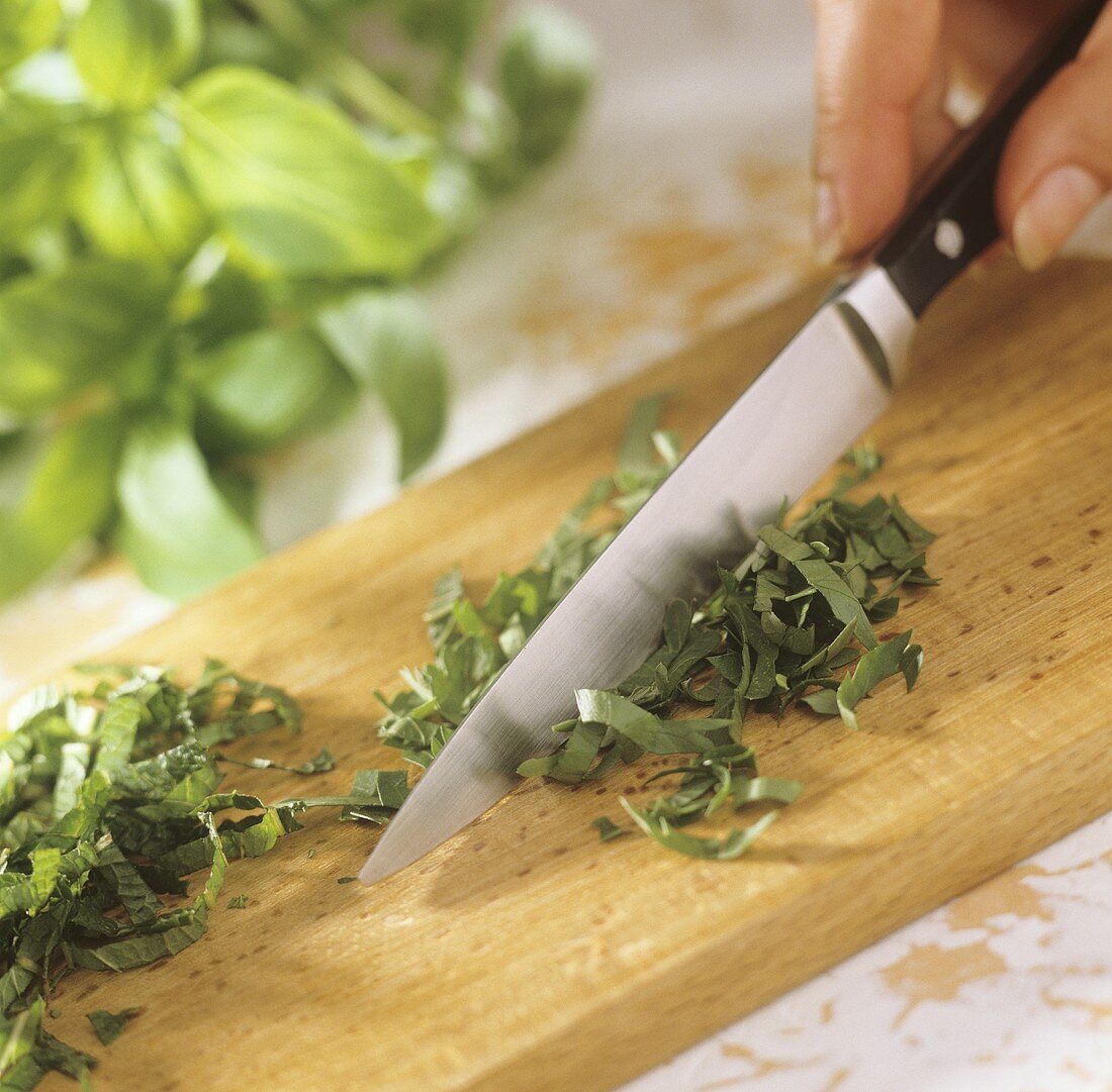 Finely chopping mint and basil leaves