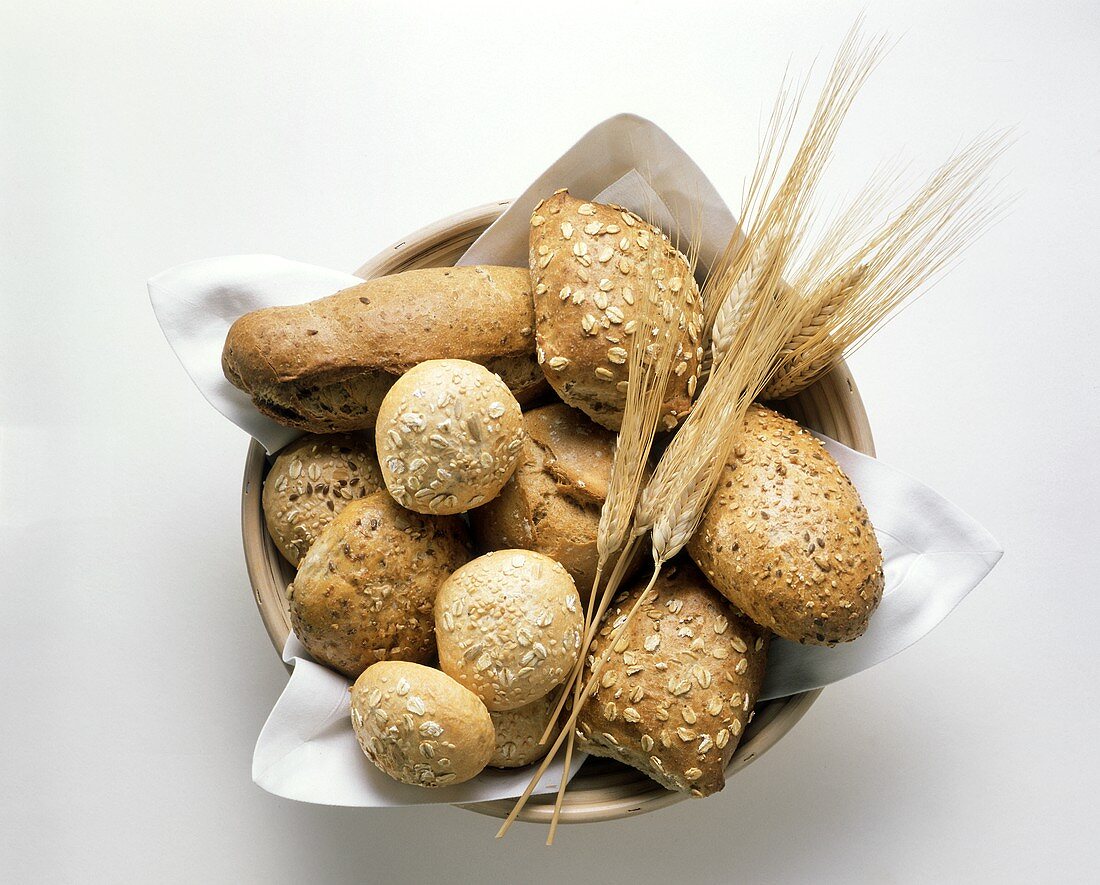 Wholemeal rolls in bread basket with ears of corn