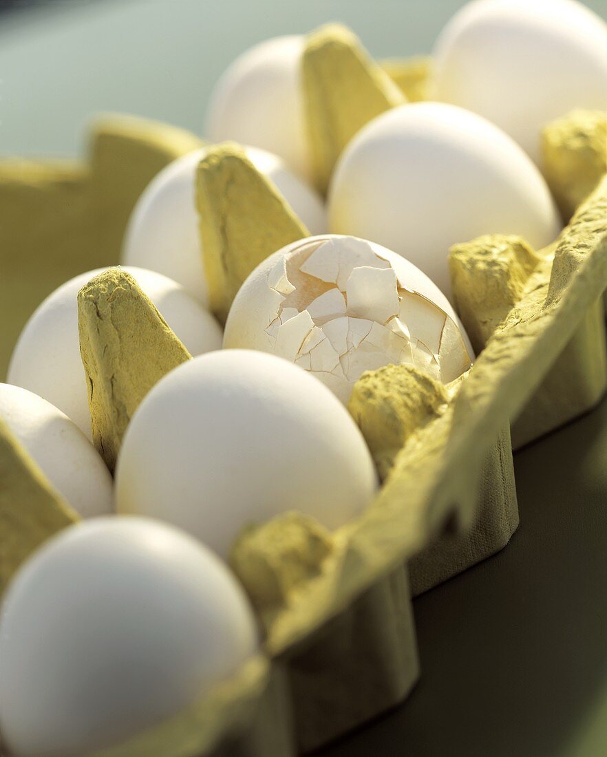 weiße Eier im Karton (ein Ei mit zerbrochener Schale)