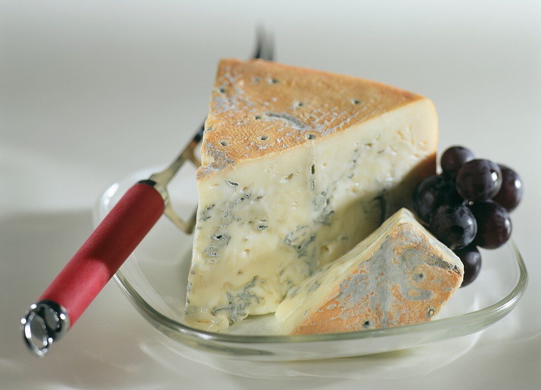 Ein Stück Gorgonzola picante mit Weintrauben und Käsemesser