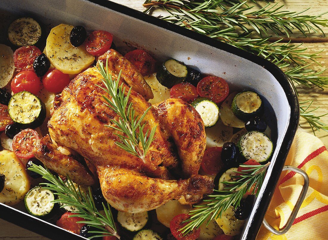 Rosemary chicken on bed of vegetables in a roasting tin