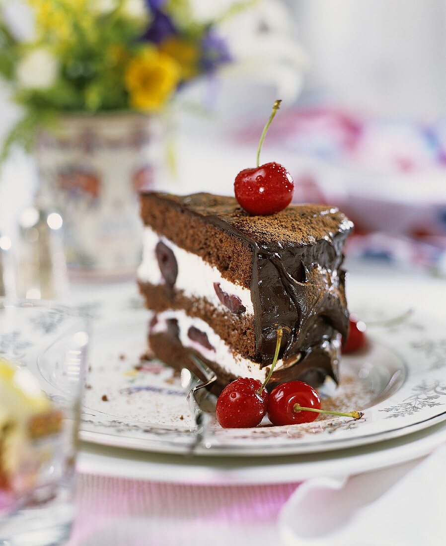 A piece of chocolate cream gateau with cherries
