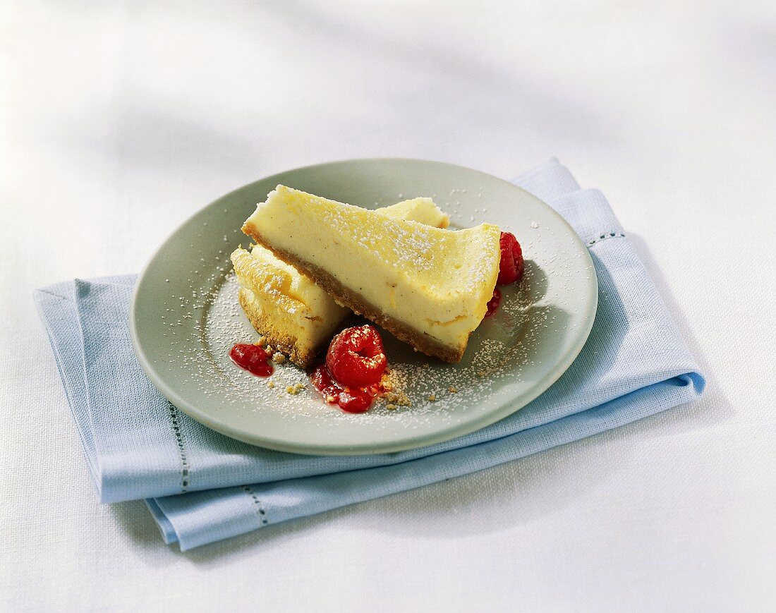 Two pieces of cheesecake with raspberries