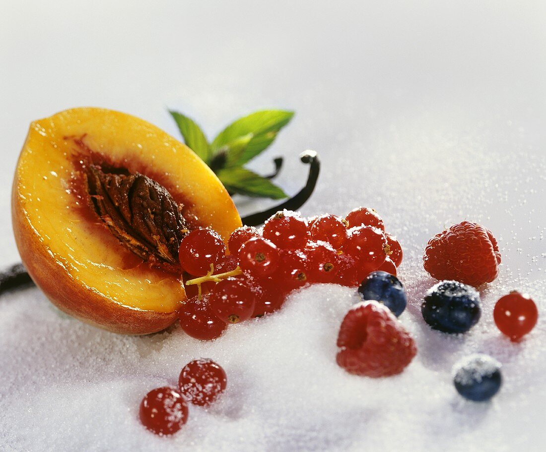 Still life with sugar, berries, peach and vanilla pod