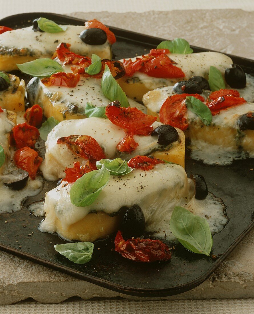 Polentahäppchen mit Tomaten, Oliven und Käse überbacken