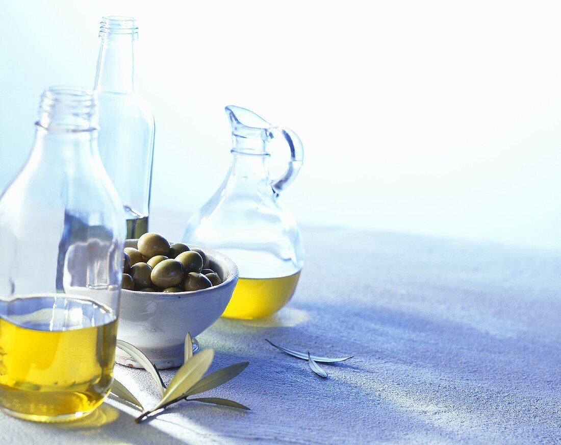 Various olive oils and a bowl of green olives