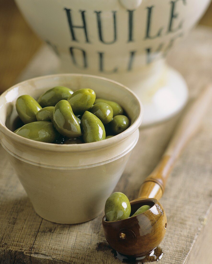 A bowl of green olives in olive oil