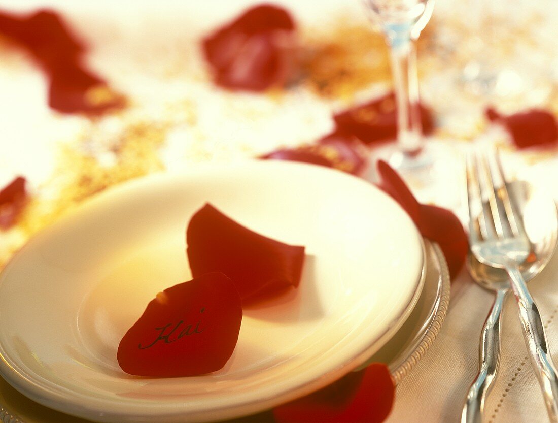 Tischgedeck mit roten Rosenblättern