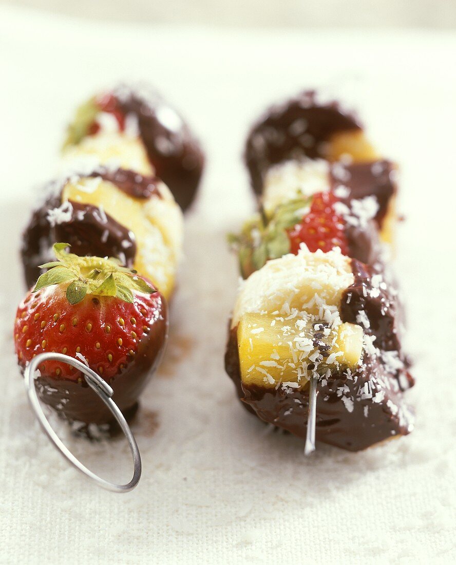 Fruit kebabs with chocolate coating and coconut flakes