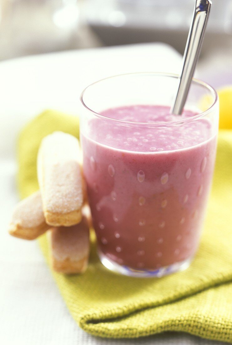 Ein Glas Beerenmilchshake, daneben Löffelbiskuits