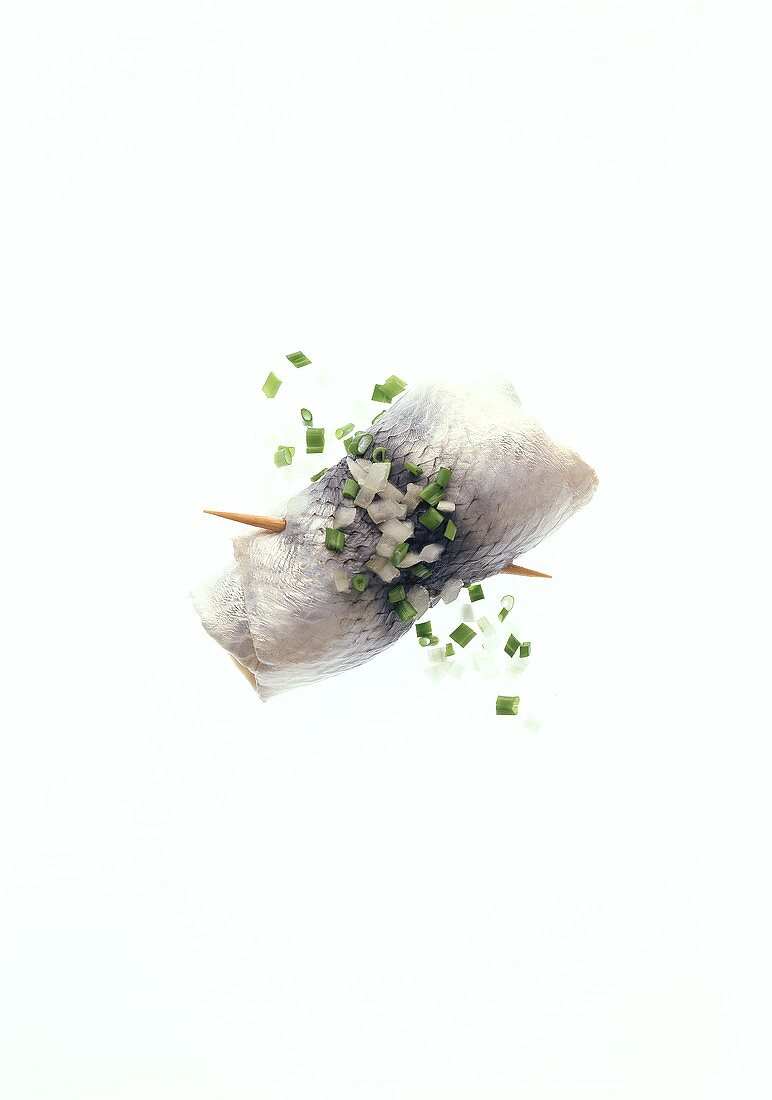 A rollmops (herring roll), onions and chives