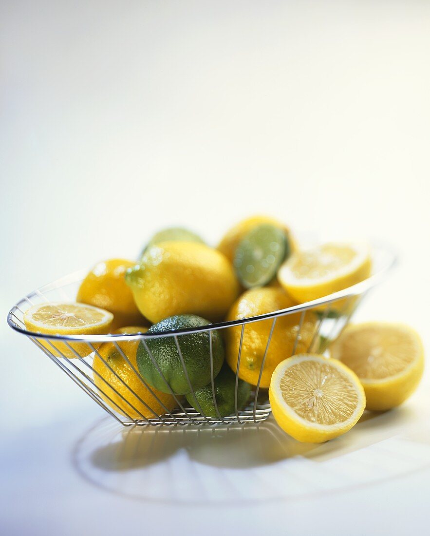 Lemons and limes, cut open and whole in wire basket