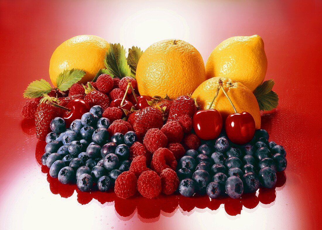 Obststillleben mit Zitrus-, Beerenfrüchten und Kirschen