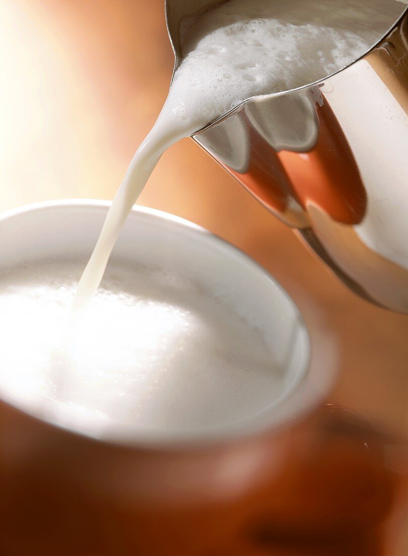 Aufgeschäumte Milch in eine Tasse gießen