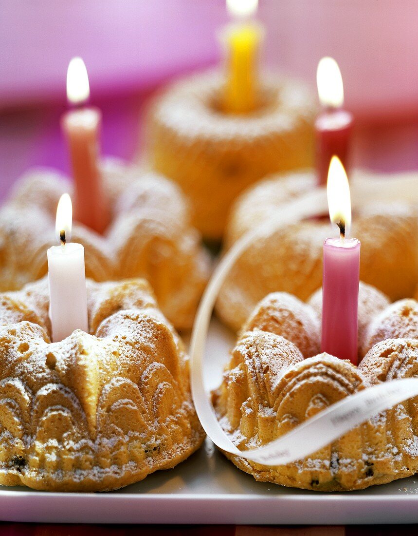 Several mini-gugelhupfs with candles on tray