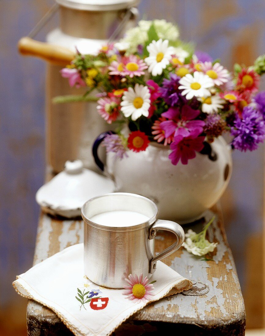Stillleben mit Milch aus der Schweiz, Serviette und Blumen
