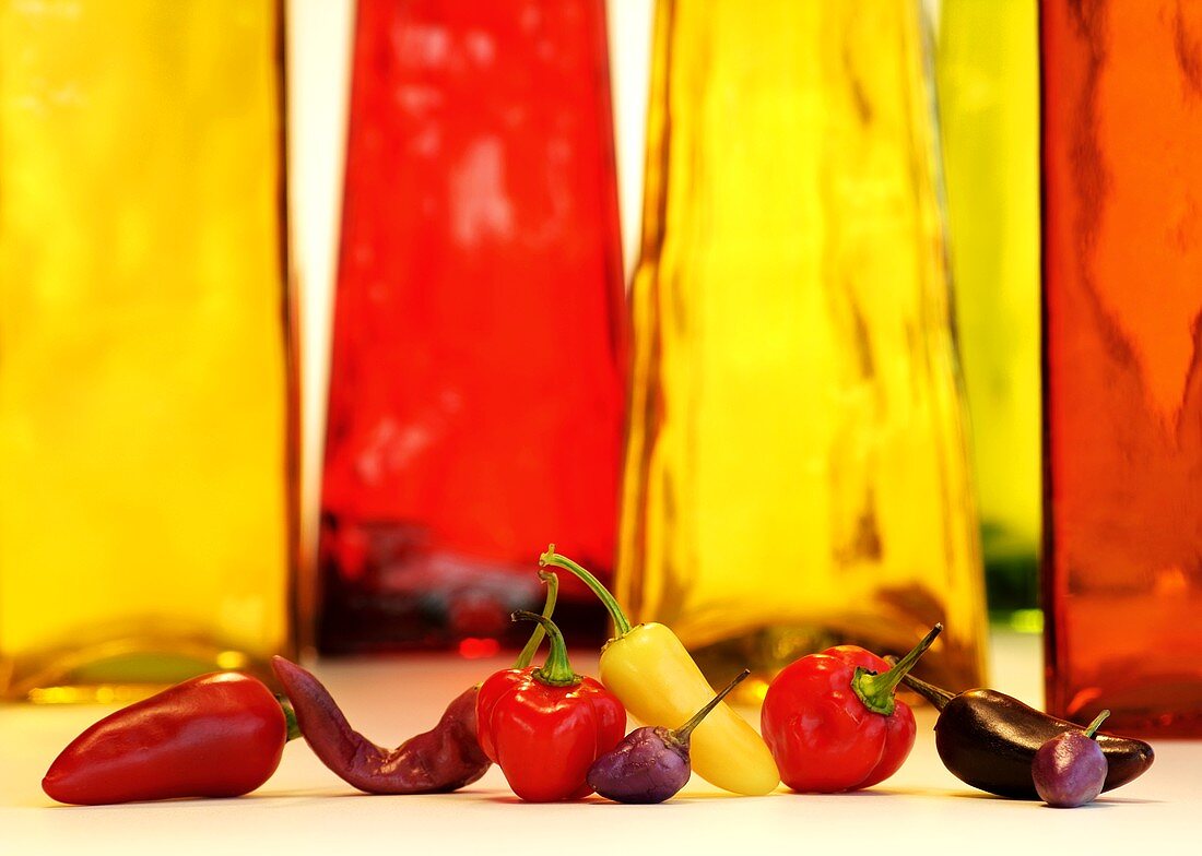 Verschiedene Paprikasorten vor roten und gelben Flaschen