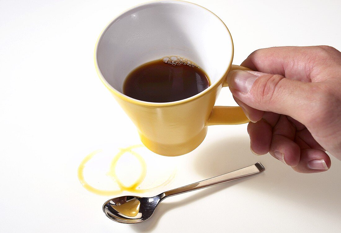Gelbe Kaffeetasse wird von einer Hand gehalten