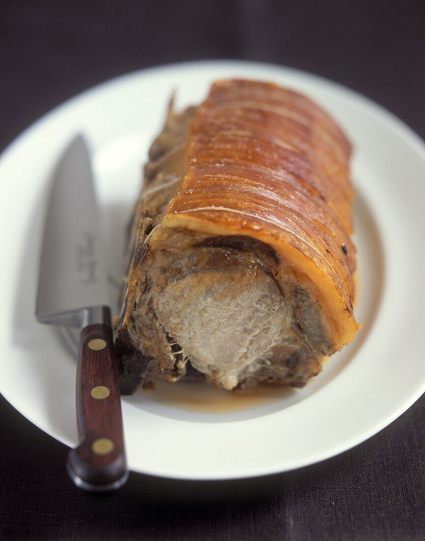 Roast pork with crackling and a knife on plate