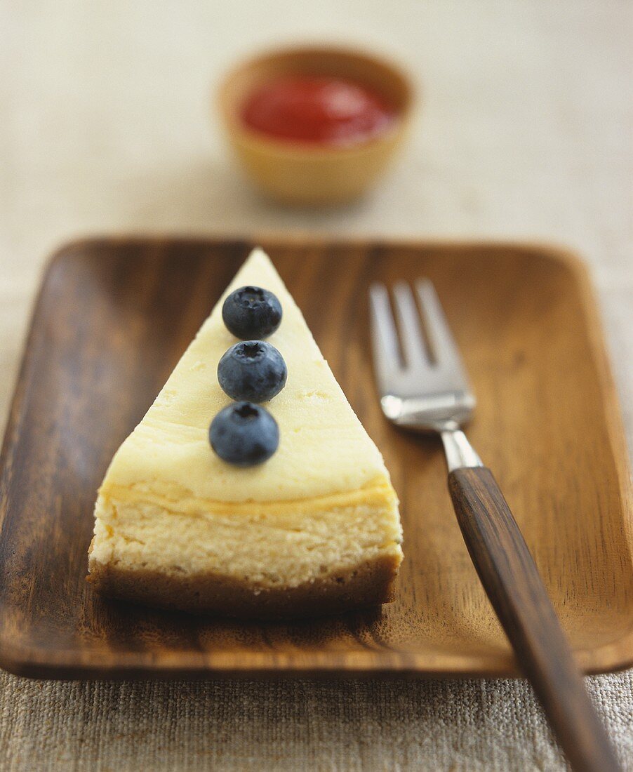 A piece of cheesecake, with blueberry garnish