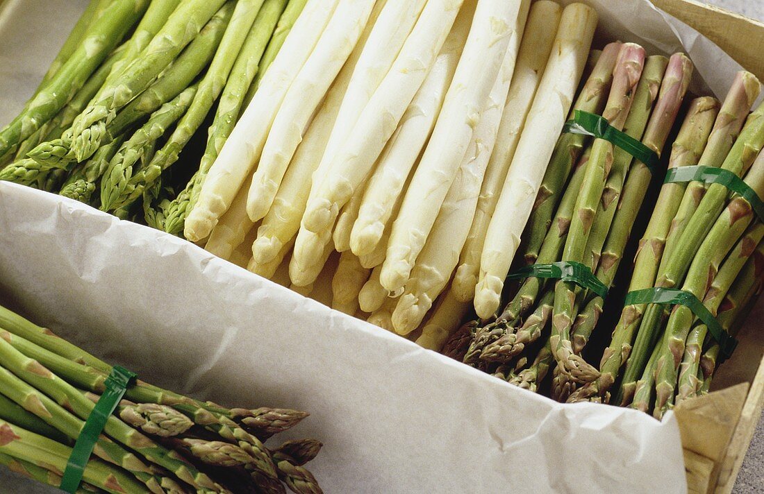 Green and white asparagus spears in a crate
