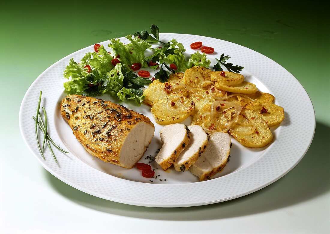 Fried chicken fillet with herbs, fried potatoes, salad